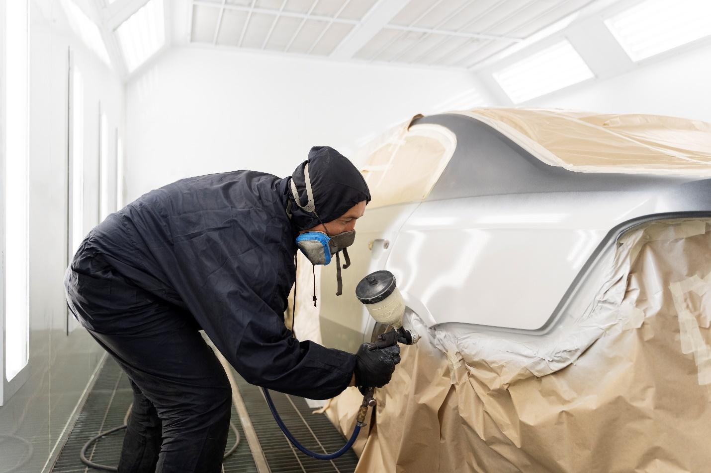 A person applying paint on the car