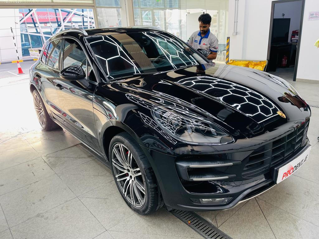 A person standing near a black shiny car