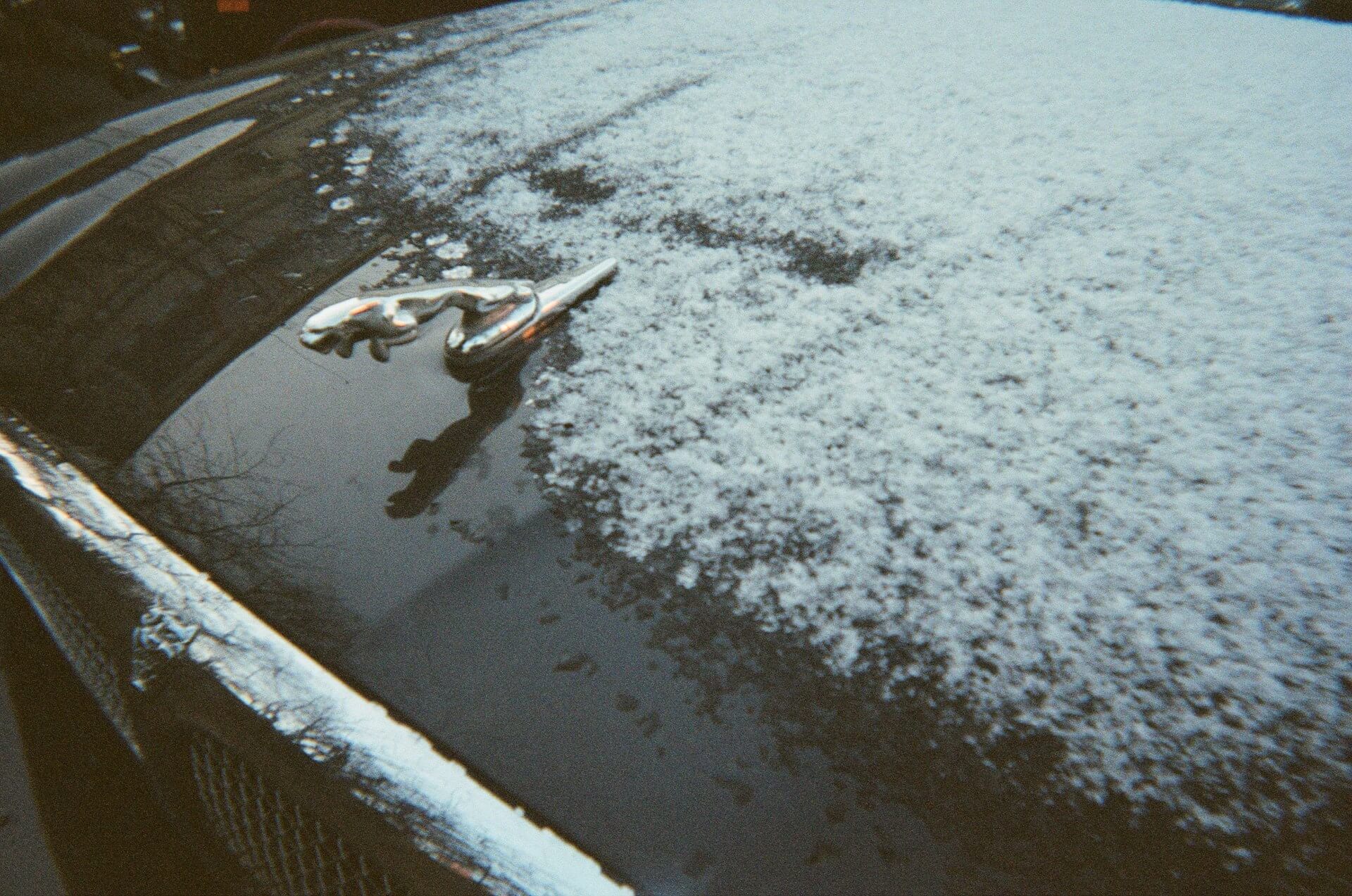 Car body buried under fresh snow next to a city parking meter